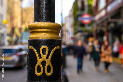 Wallpaper Mural A distinctive Westminster lamp post in outside the Covent Garden underground station, with pedestrians and cars in soft focus background. Torontodigital.ca