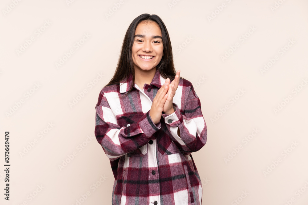 Young Indian woman isolated on beige background applauding after presentation in a conference