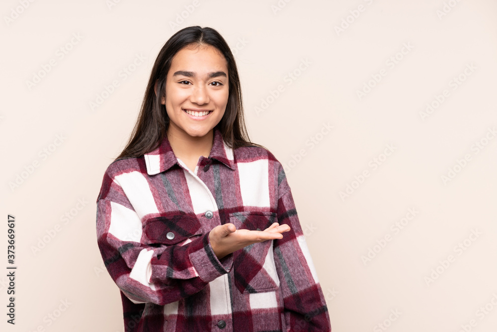 Young Indian woman isolated on beige background presenting an idea while looking smiling towards Young Indian woman isolated on beige background presenting an idea while looking smiling towards