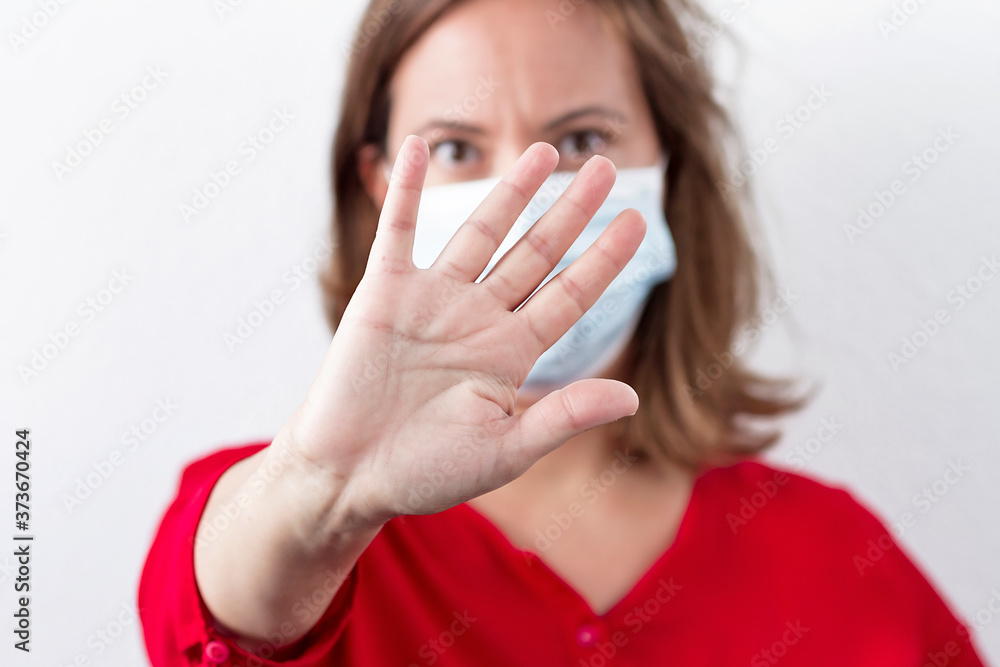 A woman with a mask making a gesture of protection and distance against Covid-19 virus A woman with a mask making a gesture of protection and distance against Covid-19 virus
