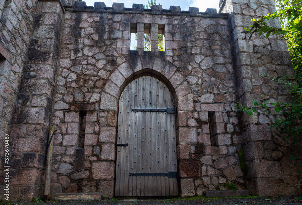 Heavy wooden castle single door with metal bands and studs.  Medieval style set in a stone block wall