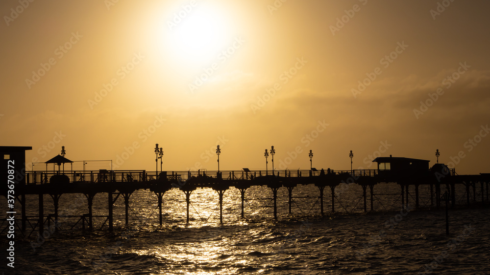 Pier silhouetted by the summer sunrise