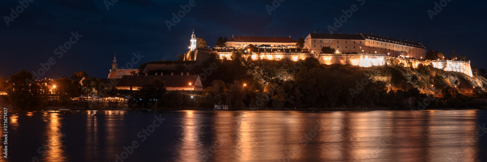 Petrovaradin fortress in Novi Sad, Serbia illuminated with colorful street lights and reflection in the Danube river water