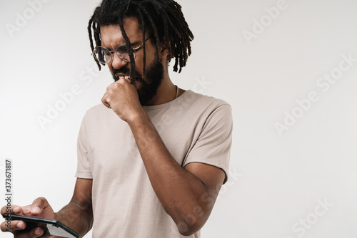Nervous african guy playing games by mobile phone