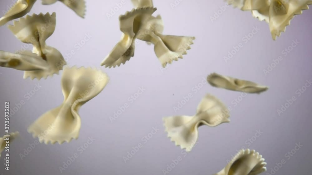 Italian striped pasta Farfalle is flying up on a white background in slow motion Italian striped pasta Farfalle is flying up on a white background in slow motion