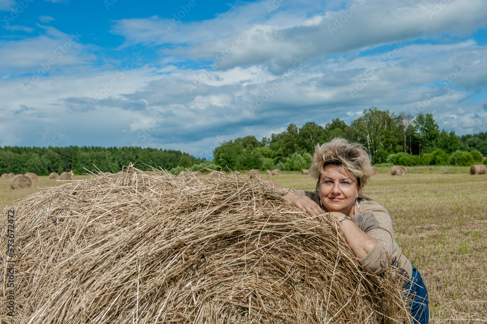 Mature beautiful woman with a bouquet of wild flowers on a mown wheat field. Active recreation, perfect maturity Mature beautiful woman with a bouquet of wild flowers on a mown wheat field. Active recreation, perfect maturity