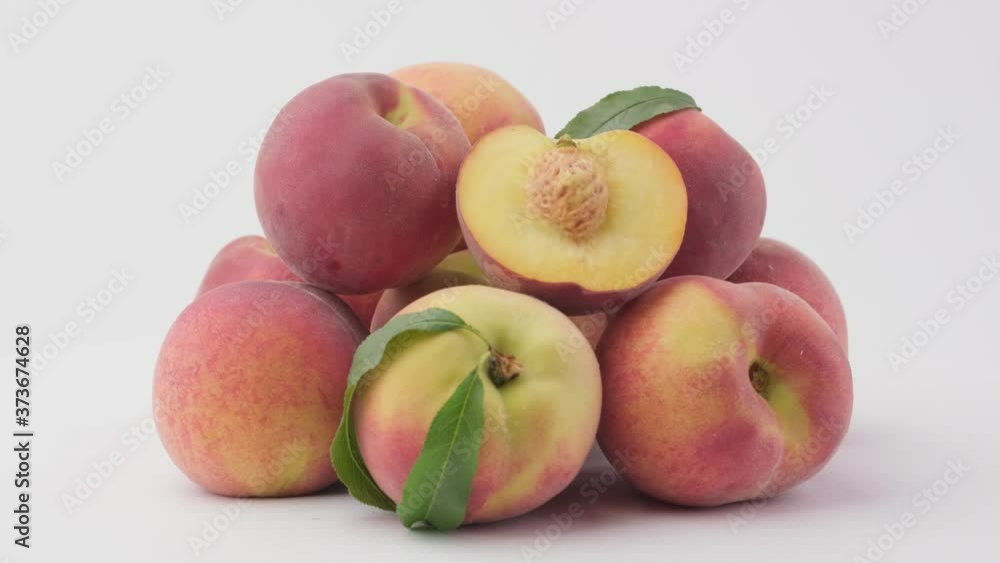 Heap of ripe peach fruit with leaves rotates on a white background, side view Heap of ripe peach fruit with leaves rotates on a white background, side view