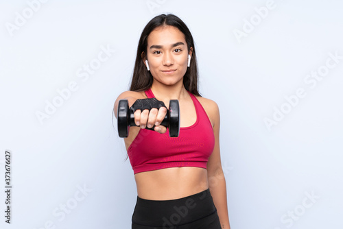 Young Indian sport woman isolated on blue background making weightlifting