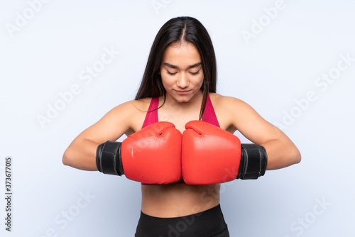 Young Indian sport woman isolated on blue background with boxing gloves