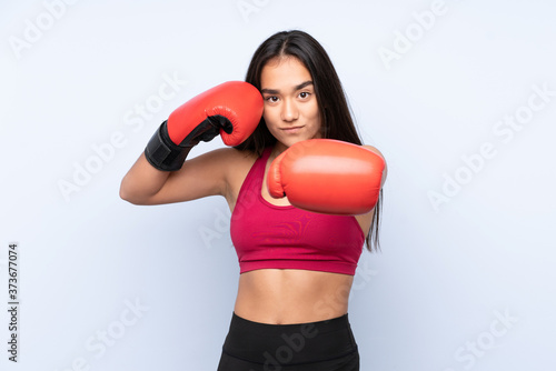 Young Indian sport woman isolated on blue background with boxing gloves © luismolinero
