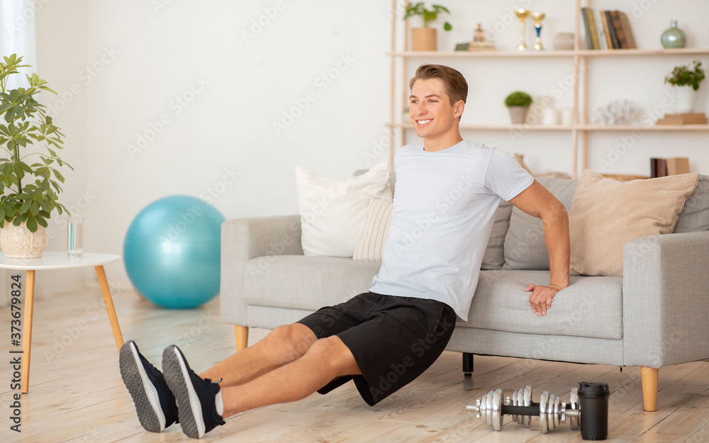 Hard work of athlete at home to keep fit. Guy leans on sofa and does exercise Hard work of athlete at home to keep fit. Guy leans on sofa and does exercise