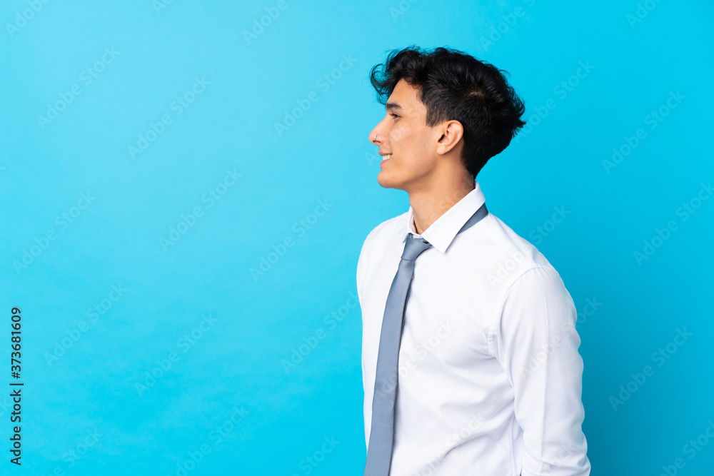 Young Argentinian businessman over isolated blue background looking to the side Young Argentinian businessman over isolated blue background looking to the side