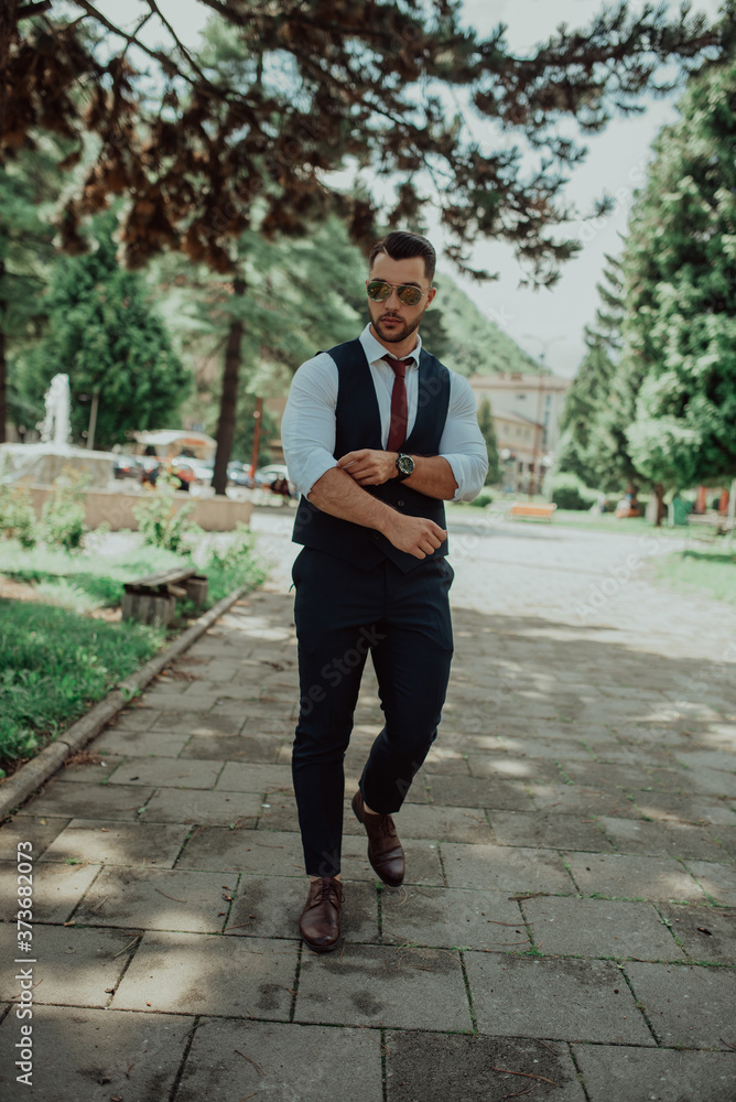 a young sexy businessman in a suit walk in park