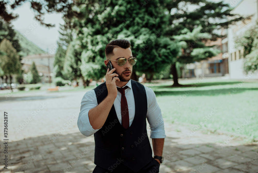 a young sexy businessman in a suit talking on smartphone a young sexy businessman in a suit talking on smartphone
