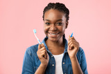Black Woman With Brackets Holding Toothbrushes Posing On Pink Background