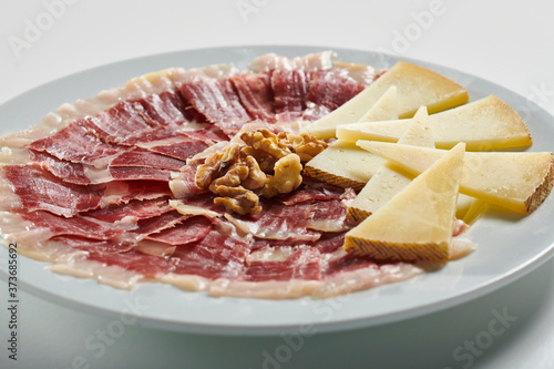 Plate of Serrano ham and manchego cheese on white background