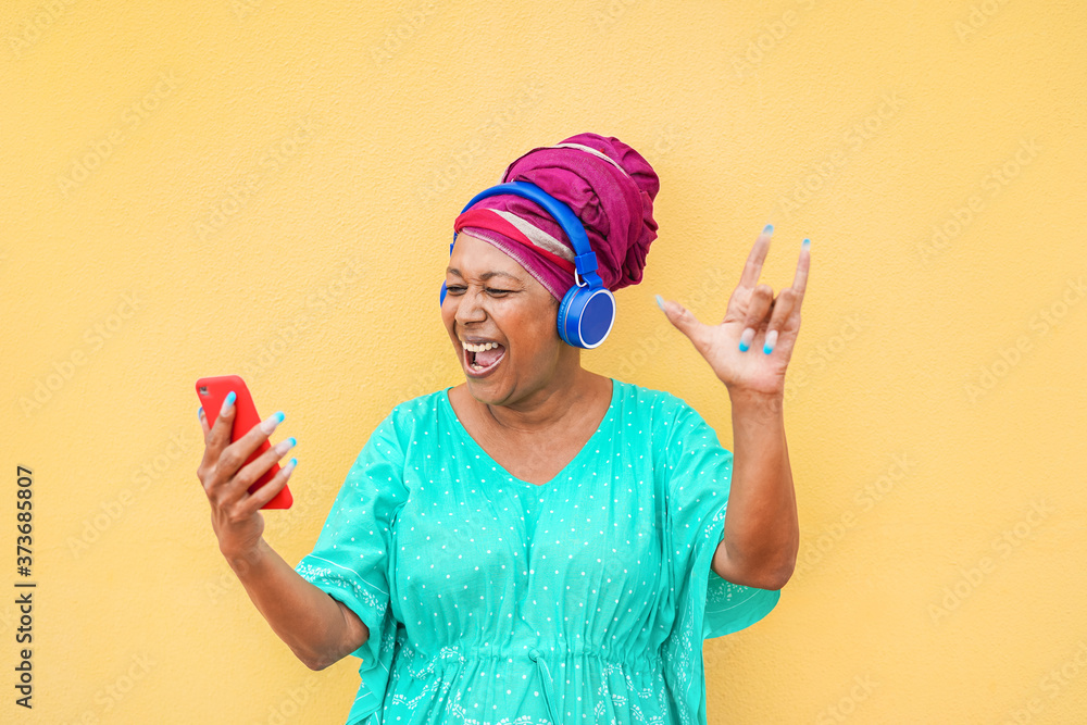 Mature african woman using smartphone app for creating playlist with rock music - Senior female having fun with mobile phone technology - Tech and joyful elderly lifestyle concept - Focus on face Mature african woman using smartphone app for creating playlist with rock music - Senior female having fun with mobile phone technology - Tech and joyful elderly lifestyle concept - Focus on face