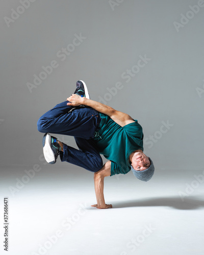 Stylish b-boy dancing on the floor in studio isolated on gray background. Breakdancing school poster