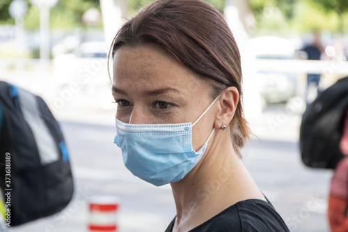 Street portrait of a woman in a medical mask, looking away, close-up, selective focus.