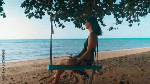Carefree happy woman on swing relax and enjoying sea on tropical beach