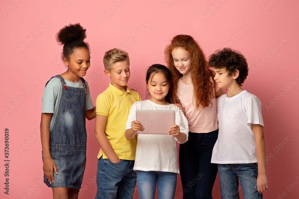 Multinational young students using tablet computer to study together over pink background Multinational young students using tablet computer to study together over pink background