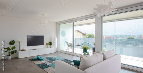 Modern living room with designer furniture. Sofa with light cushions and balcony view