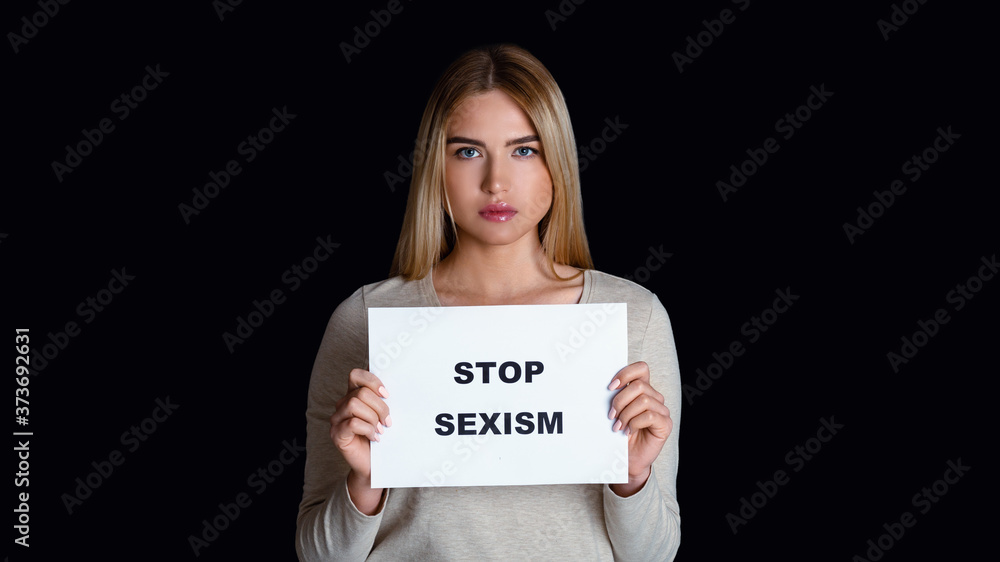Equal opportunities for women and men. Sad girl holds sign with inscription stop sexism Equal opportunities for women and men. Sad girl holds sign with inscription stop sexism