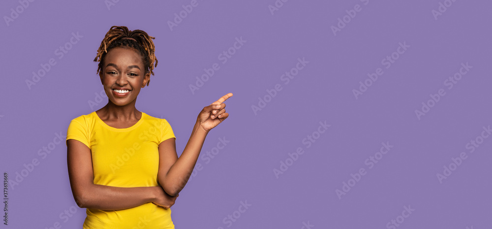 Happy black girl pointing at copy space over purple Happy black girl pointing at copy space over purple
