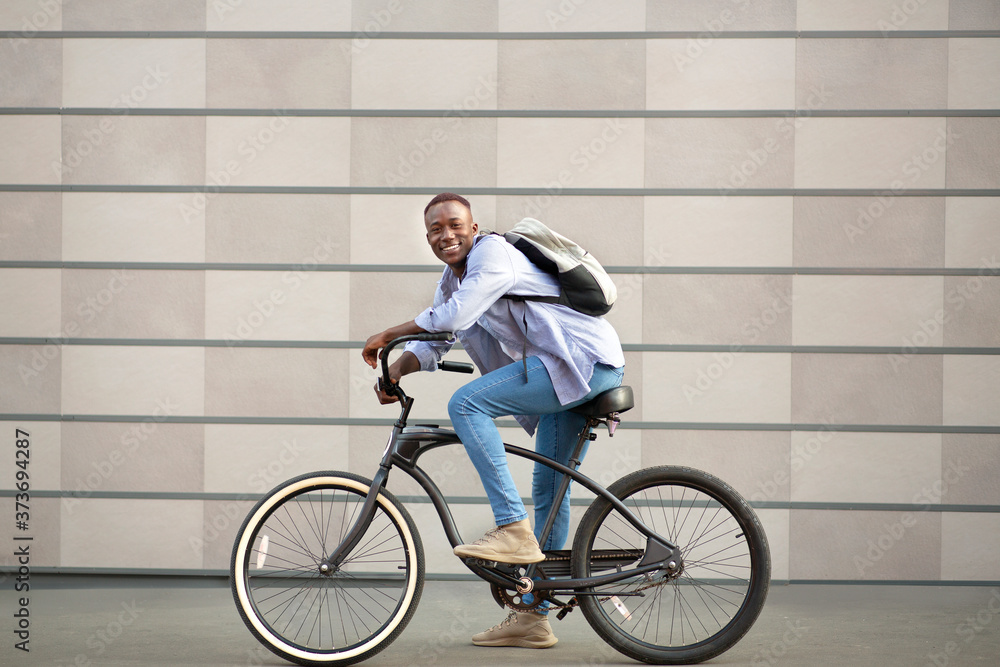 Portrait of joyful black guy with bicycle near brick wall outside Portrait of joyful black guy with bicycle near brick wall outside