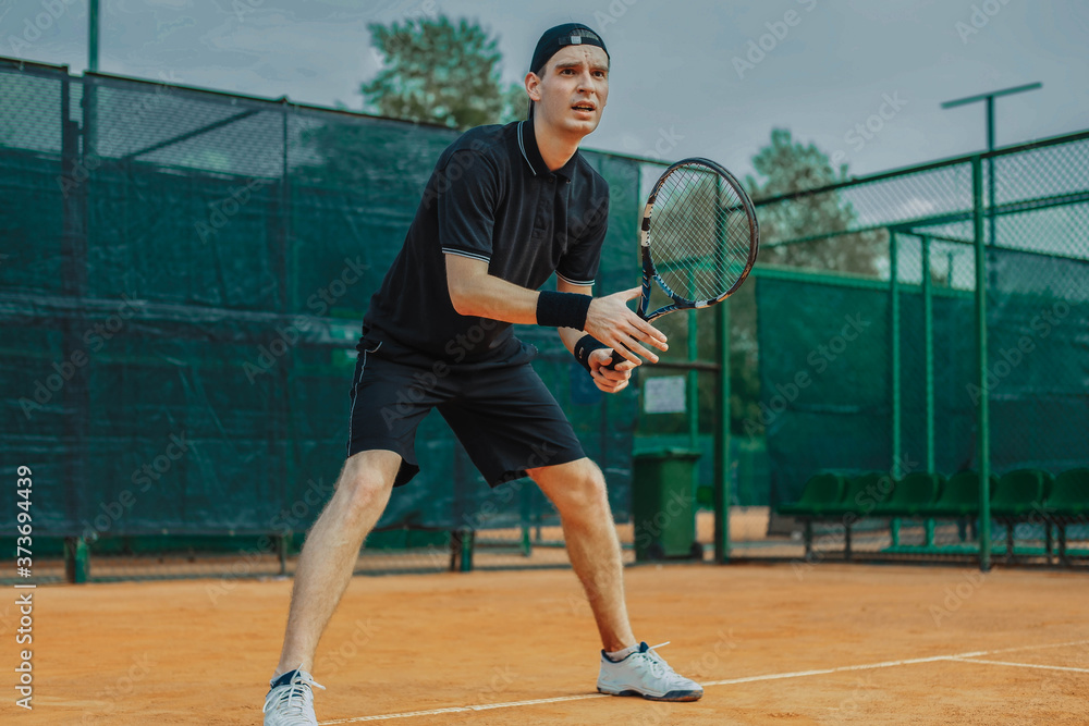 Distant plan of Man Holding Racket In Both Hands To Straighten Strike While Waiting For Ball Serving At Tennis Court.