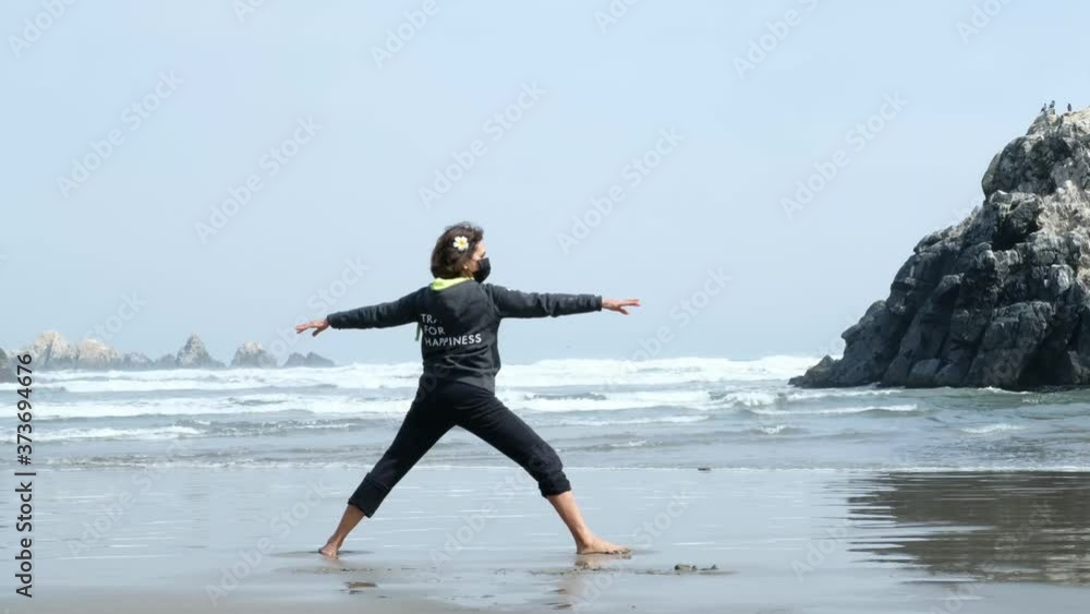 woman practicing yoga on the beach while wearing black protective mask. covid 19 concept. outdoors yoga woman practicing yoga on the beach while wearing black protective mask. covid 19 concept. outdoors yoga