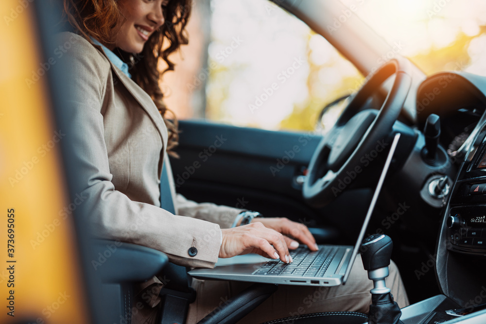 Beautiful young businesswoman driving car and using laptop. Beautiful young businesswoman driving car and using laptop.