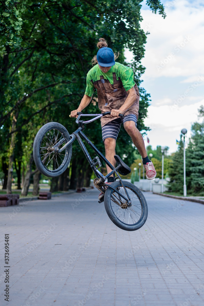 Fototapeta premium A bmx cyclist makes a jump stunt in the middle of a city alley. Extreme cycling.