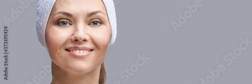 Happy woman beauty portrait. Cosmetology face product. Rejuvenation skin mask. Facial skincare cosmetics. Perfect female smile. Horizontal banner with copyspace. Grey background. Plastic concept