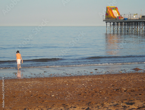 Girl Paddles in Sea in Evening near Pier