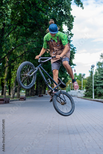 A bmx cyclist makes a jump stunt in the middle of a city alley. Extreme cycling.
