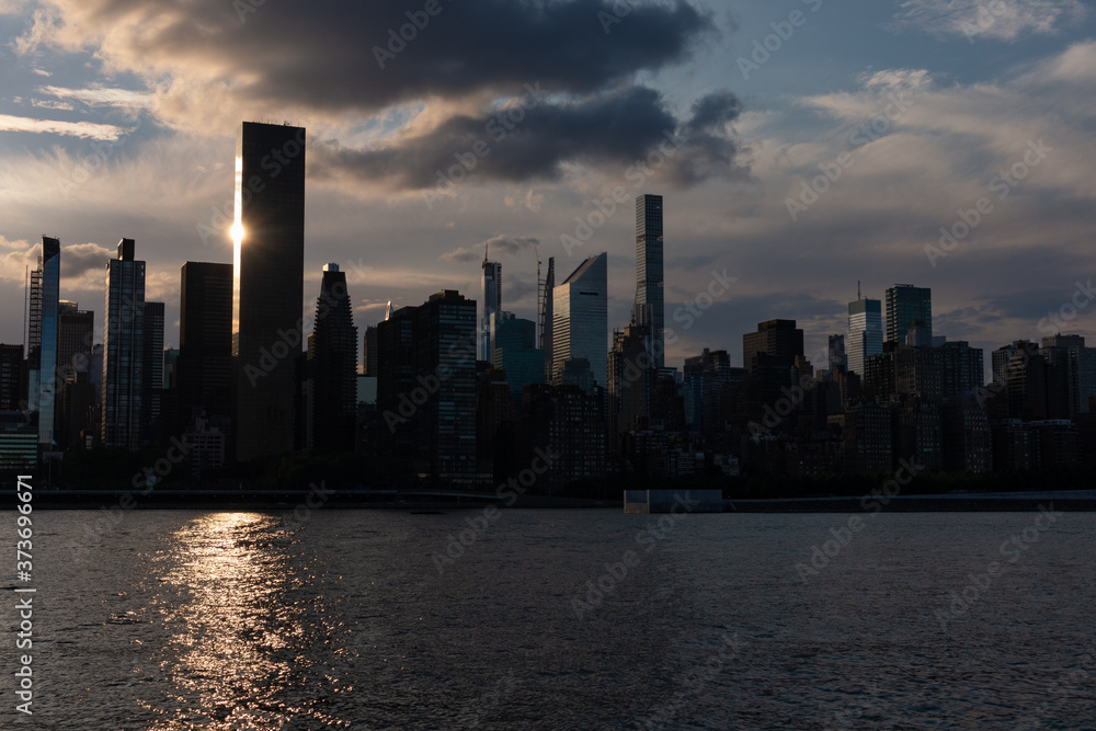 Fototapeta premium Beautiful Silhouettes of Skyscrapers in the Midtown Manhattan Skyline during a Sunset along the East River in New York City
