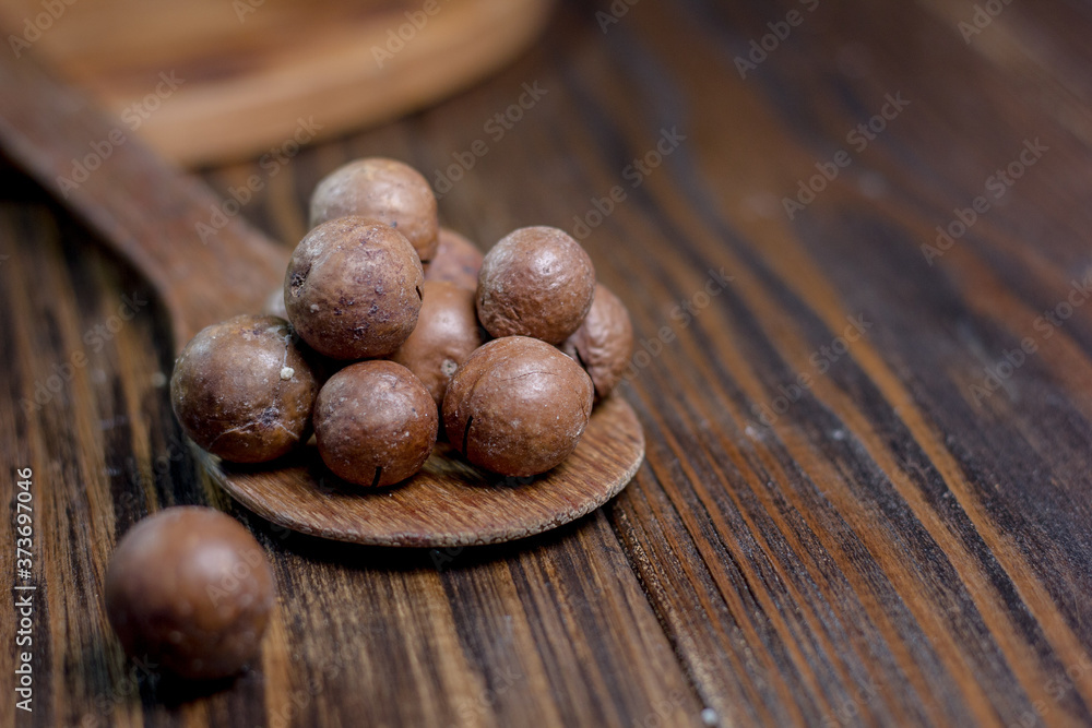 Macadamia nuts on the wooden spoon over the wooden table. Macadamia nuts on the wooden spoon over the wooden table.