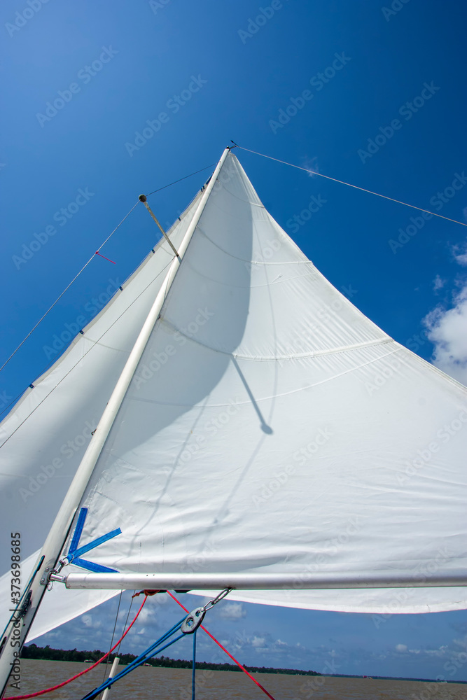 Mastro de veleiro com vela inflada pelo vento em dia ensolarado. Barco navegando