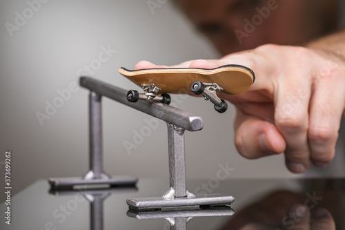 Man rolls a fingerboard on a gray metal railing