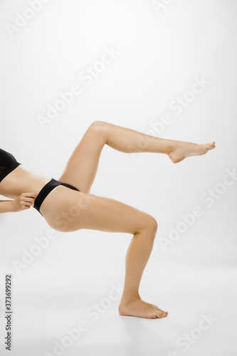 Beautiful female legs and belly isolated on white background. Beauty, cosmetics, spa, depilation, treatment and fitness concept. Fit and sportive, sensual body with well-kept skin in underwear.