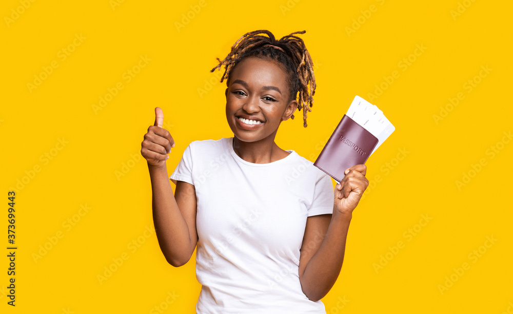 Happy young black girl holding passport and tickets Happy young black girl holding passport and tickets