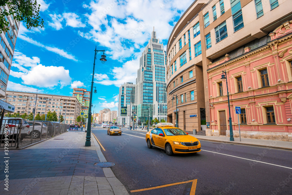 Fototapeta premium Moscow / Russia - 16 Aug 2020: Automobile stream and yellow taxi near the business building, multifunctional business center, high-rise building in Moscow