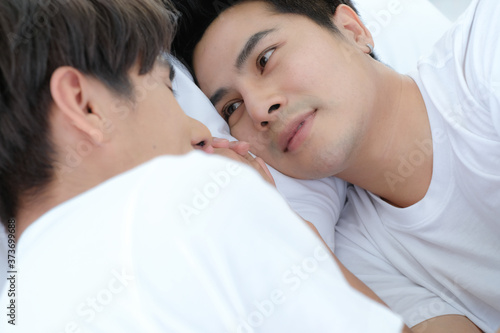 Asian handsome man Lgbt couple lovers hold hands and look each other on bed with happiness and love.