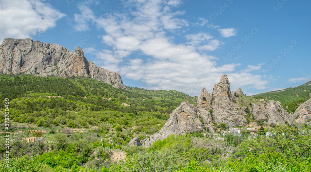 Rocks between green valleys. Road, small houses hidden in the trees. Nice panorama with beautiful clouds and sunny day. Krim