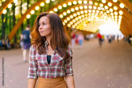 Portrait of a young girl in a shirt in Sokolniki Park in Moscow under an arch with lanterns © KseniaJoyg