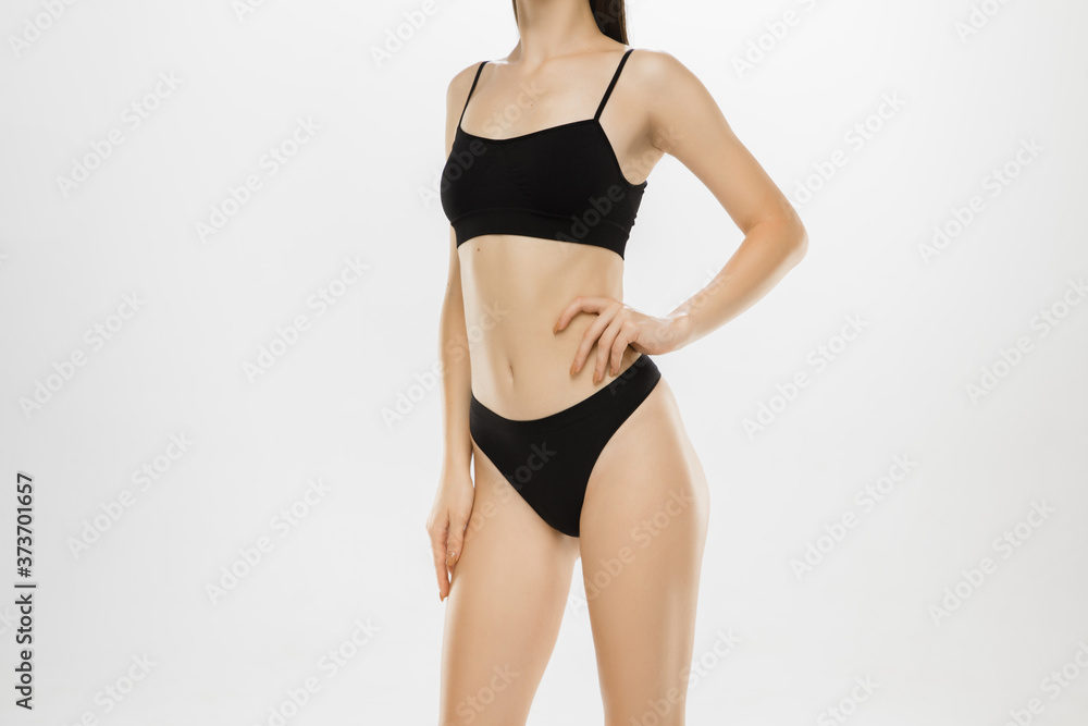 Fototapeta premium Beautiful female legs and belly isolated on white background. Beauty, cosmetics, spa, depilation, treatment and fitness concept. Fit and sportive, sensual body with well-kept skin in underwear.