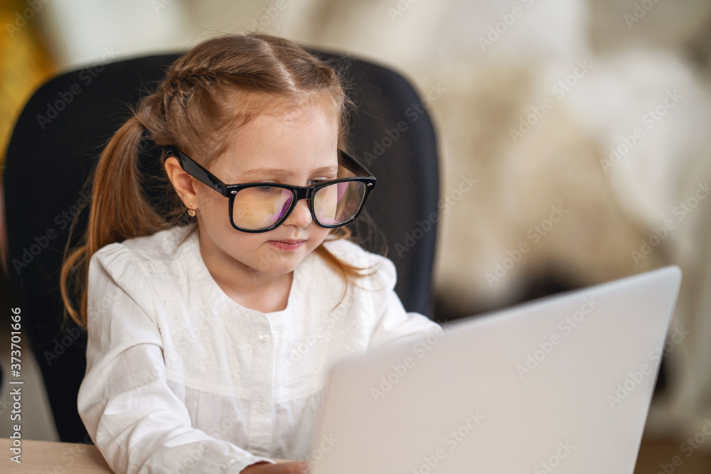 little girl with glasses using the digital concept of e-learning using a laptop. little girl with glasses using the digital concept of e-learning using a laptop.
