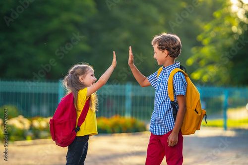 Primary school pupil. boy and a girl with backpacks are walking down the street.