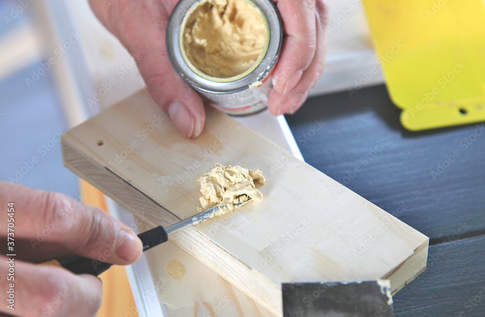 woodwork. Closeup putty cans in man's hand. DIY worker applying filler